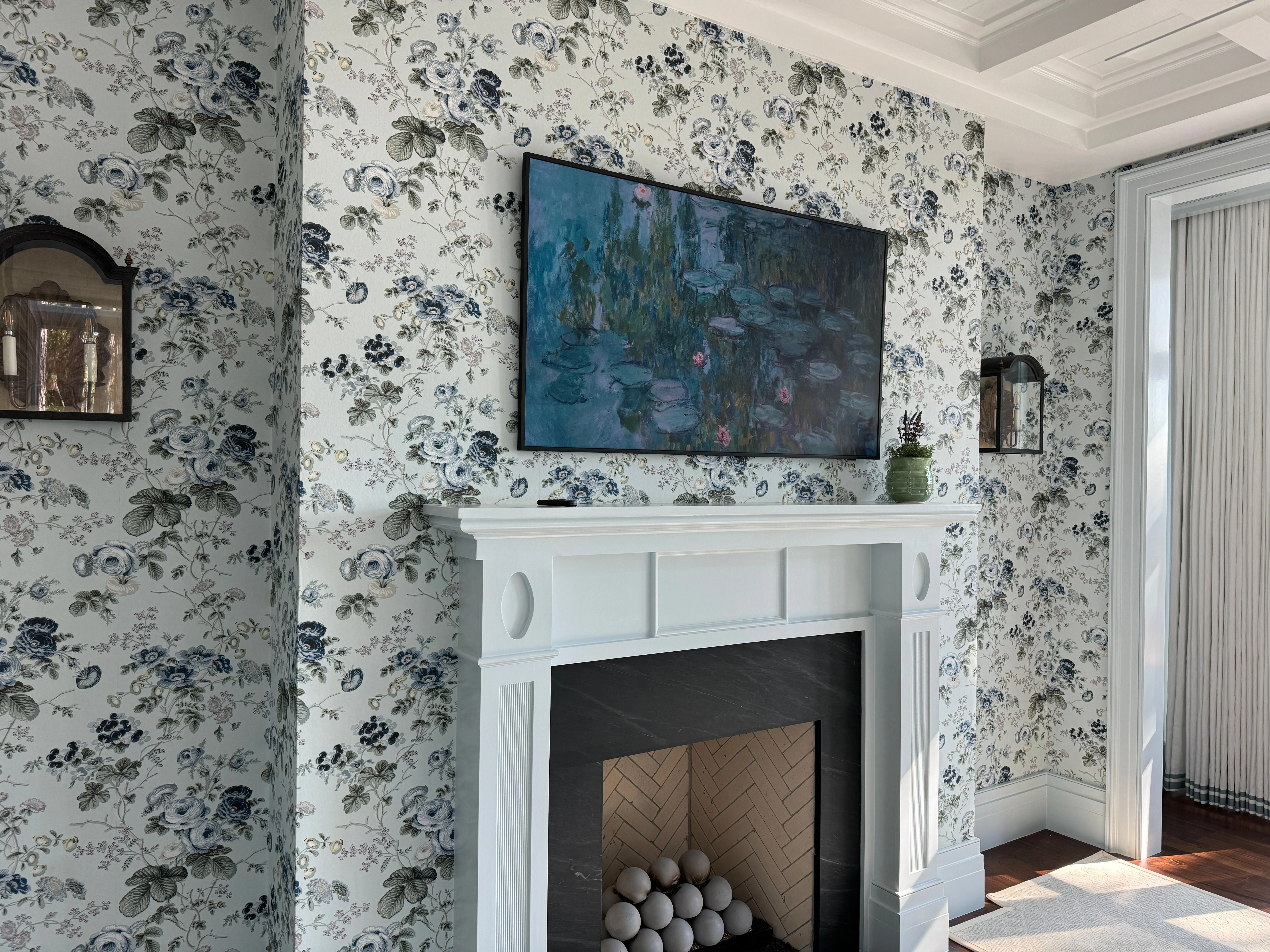 Black-and-white floral wallcovering framing a bright fireplace